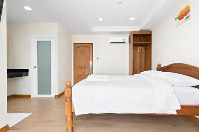 a bedroom with a bed with white sheets and a tv at Royale 8 Ville Guest House in Bangkok