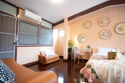 a bedroom with a bed and a desk and a chair at Dunah's Garden Home in Bangkok