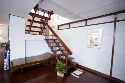 a wooden spiral staircase in a room with a bench at Dunah's Garden Home in Bangkok