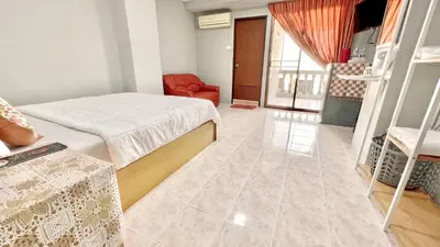 a bedroom with two beds and a red chair at Penyos Suite in Bangkok