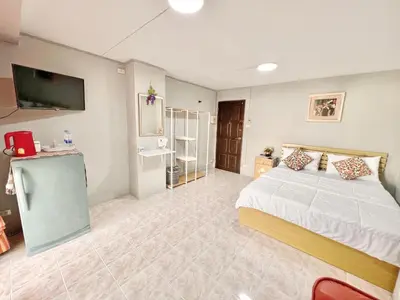 a large bedroom with a bed and a tv at Penyos Suite in Bangkok