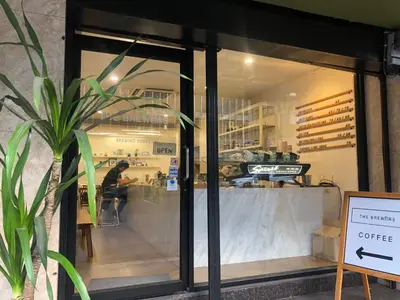 a coffee shop with a person sitting at a table in the window at Rajparop PLace in Bangkok
