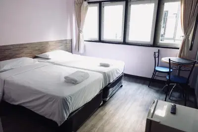 a hotel room with a bed and a table and windows at Rajparop PLace in Bangkok