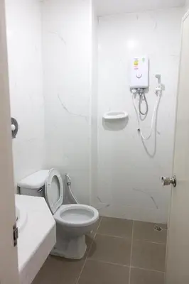 a white bathroom with a toilet and a shower at Rajparop PLace in Bangkok