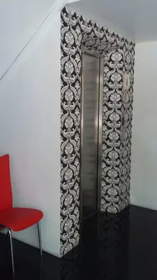 a metal elevator in a room with a red chair at @Room Apartment in Bangkok