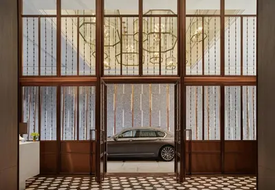 a car is seen through a glass door at Rosewood Bangkok in Bangkok