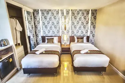 three beds in a room with a tv and curtains at The Aim Sathorn Hotel in Bangkok