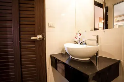a bathroom with a white sink on a black counter at The Aim Sathorn Hotel in Bangkok
