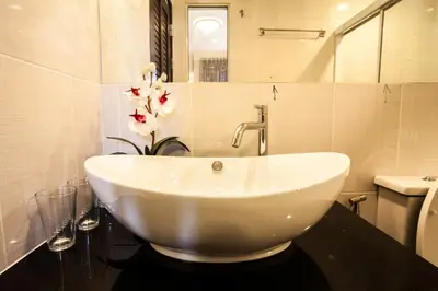 a bathroom with a white sink and a toilet at The Aim Sathorn Hotel in Bangkok