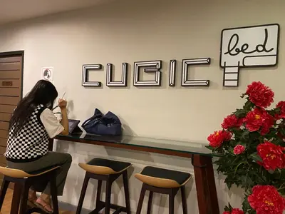 a woman sitting at a bar in a waiting room at Cubic Bed Pratunam in Bangkok