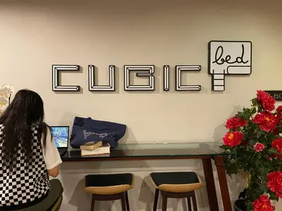 a woman sitting at a desk in a food chef store at Cubic Bed Pratunam in Bangkok