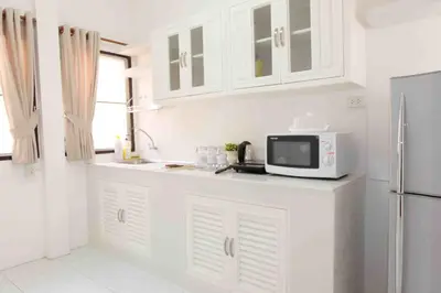 a white kitchen with a microwave and a refrigerator at Chatuchak Art & Nature House ( 3-6 pers.) in Bangkok