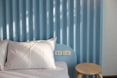 a bed with a white pillow and a wooden table at Boxpackers Hostel Phranakorn in Bangkok