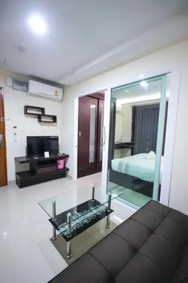 a living room with a glass coffee table and a television at The Cosy River in Bangkok