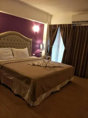 a bedroom with a large bed with a purple wall at Infinite Hotel in Bangkok