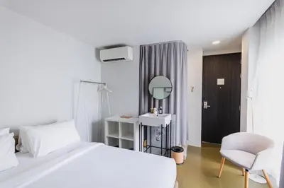 a white bedroom with a white bed and a chair at Chocolate box mint in Bangkok