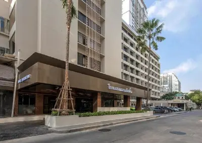 a building with a tower next to a palm tree at Manhattan Hotel Bangkok in Bangkok