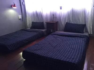 a room with two beds and a table at Hong hostel in Bangkok