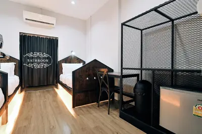 a room with two beds and a desk in it at Castle Black Bangkok in Bangkok