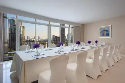 a long white table with white chairs and purple flowers at Dusit Suites Hotel Ratchadamri, Bangkok in Bangkok