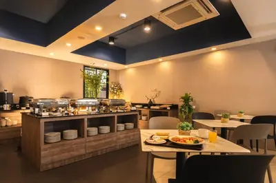 a restaurant with tables and a counter with food at The Home Hotel SHA in Bangkok