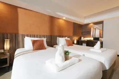 two beds in a hotel room with white sheets at The Home Hotel SHA in Bangkok