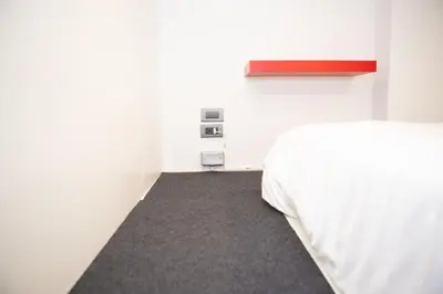 a bedroom with a white bed and a gray carpet at Rich8 Hostel in Bangkok