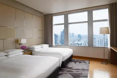a hotel room with two beds and a large window at Marriott Executive Apartments Bangkok, Sukhumvit Thonglor in Bangkok