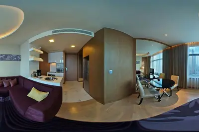 a living room with a purple couch and a kitchen at Marriott Executive Apartments Bangkok, Sukhumvit Thonglor in Bangkok