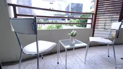 two chairs and a table in a room with a window at Ploenchit Mansion in Bangkok