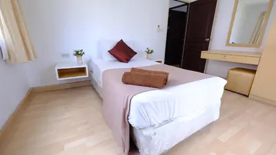 a bedroom with two beds with white sheets and red pillows at Ploenchit Mansion in Bangkok