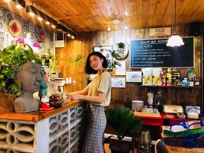 a woman standing at a counter in a coffee shop at Nego Home Ancient Inn in Bangkok