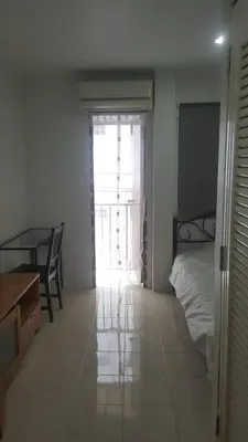 a bedroom with a bed and a table and a window at JS mansion in Bangkok