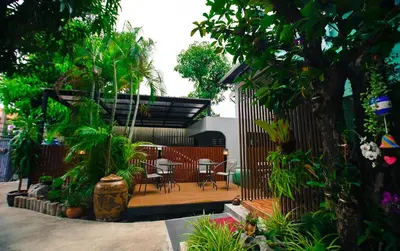 a wooden deck with chairs and a table in a garden at Bed garden 26 in Bangkok