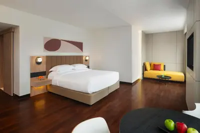a bedroom with a white bed and a yellow couch at Avani Ratchada Bangkok in Bangkok