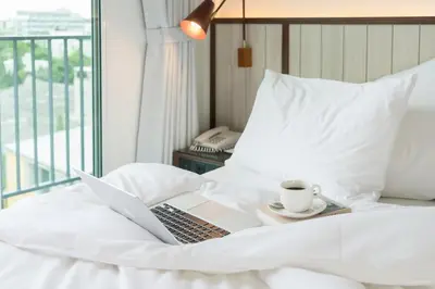 a laptop on a bed with a cup of coffee at Hotel Amber Sukhumvit 85 in Bangkok
