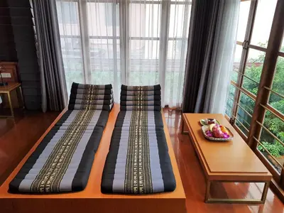 two beds in a room with a table and windows at Vali Villa Bangkok in Bangkok