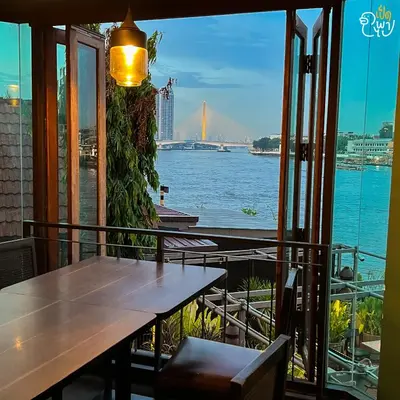a view of the water from a restaurant with a table at Baan Wanglang Riverside, Bangkok in Bangkok