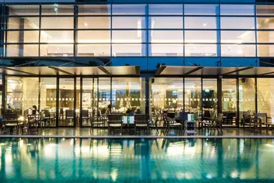 a pool with tables and chairs in a building at Holiday Inn Bangkok Sukhumvit by IHG in Bangkok