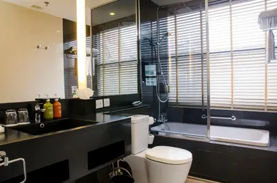 a bathroom with a toilet and a sink and a mirror at Holiday Inn Bangkok Sukhumvit by IHG in Bangkok