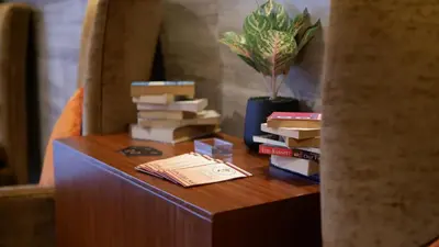 a table with books on it next to a vase with a plant at On 8 Sukhumvit Nana Bangkok in Bangkok