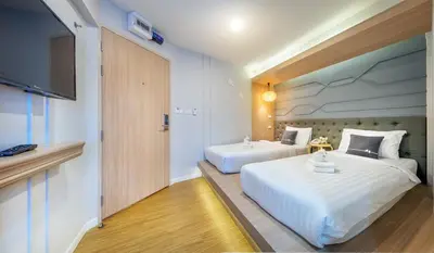 a hotel room with two beds and a flat screen tv at Tori Prestige Bangkok Hotel in Bangkok