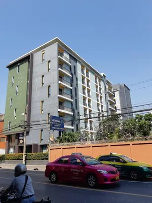 a red car driving down a street next to a building at 24Residence Siriraj in Bangkok