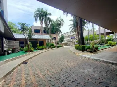 a cobblestone street with palm trees and buildings at Komol Residence Bangkok in Bangkok