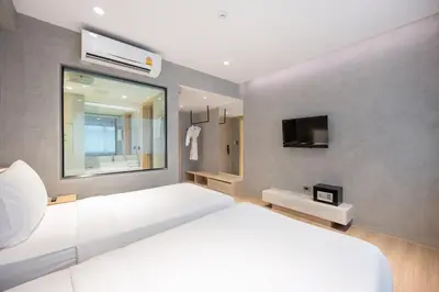 a bedroom with a white bed and a tv at Loft Bangkok Hotel in Bangkok