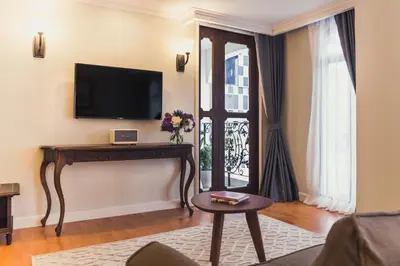 a living room with a tv and a table and a window at Daraya Boutique Hotel in Bangkok