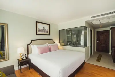 a bedroom with a large white bed with pink pillows at Daraya Boutique Hotel in Bangkok