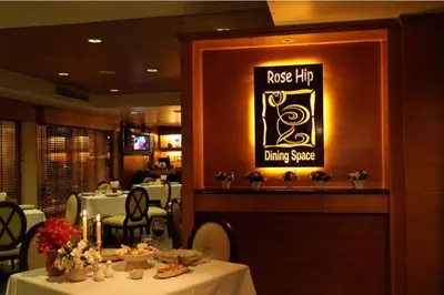 a restaurant with a dining room with tables and a sign at Rose Hotel in Bangkok