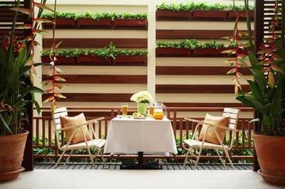 a table and chairs on a patio with plants at Rose Hotel in Bangkok