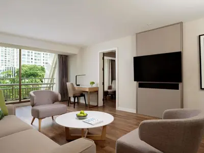 a living room with a couch and a tv at Mövenpick BDMS Wellness Resort Bangkok in Bangkok